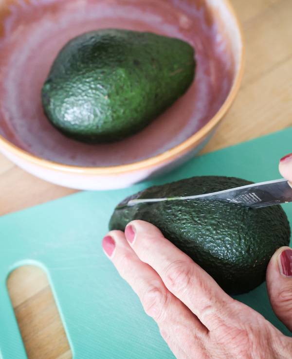 Eine Frau schneidet mit einem Messer eine Avocado auf. Die Zahlen zu Fällen von Schnittverletzungen beim Aufschneiden von Avocados sind gestiegen. (Symbolfoto)