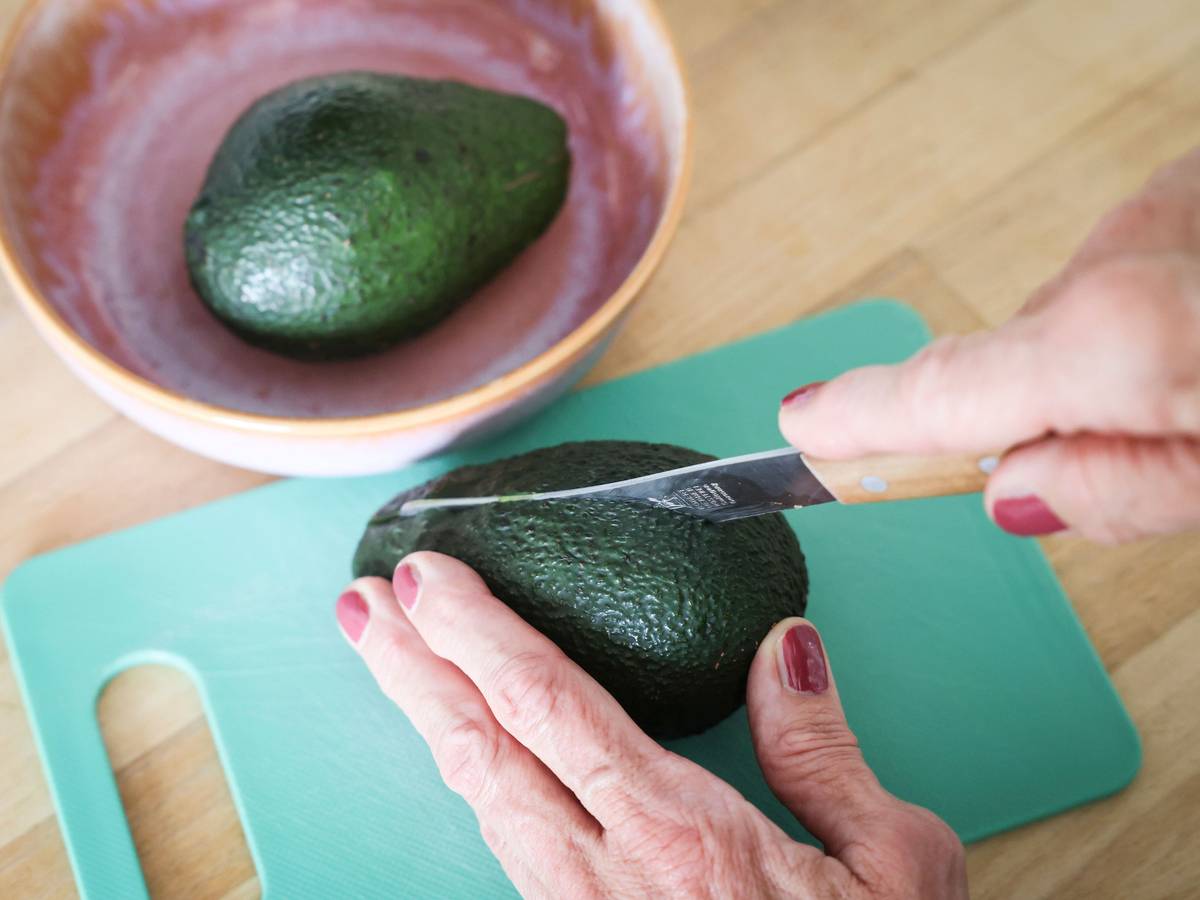 Eine Frau schneidet mit einem Messer eine Avocado auf. Die Zahlen zu Fällen von Schnittverletzungen beim Aufschneiden von Avocados sind gestiegen. (Symbolfoto)