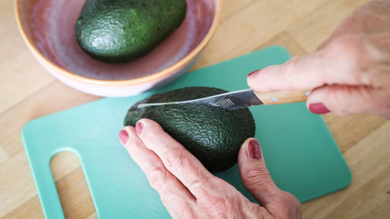 Eine Frau schneidet mit einem Messer eine Avocado auf. Die Zahlen zu Fällen von Schnittverletzungen beim Aufschneiden von Avocados sind gestiegen. (Symbolfoto)