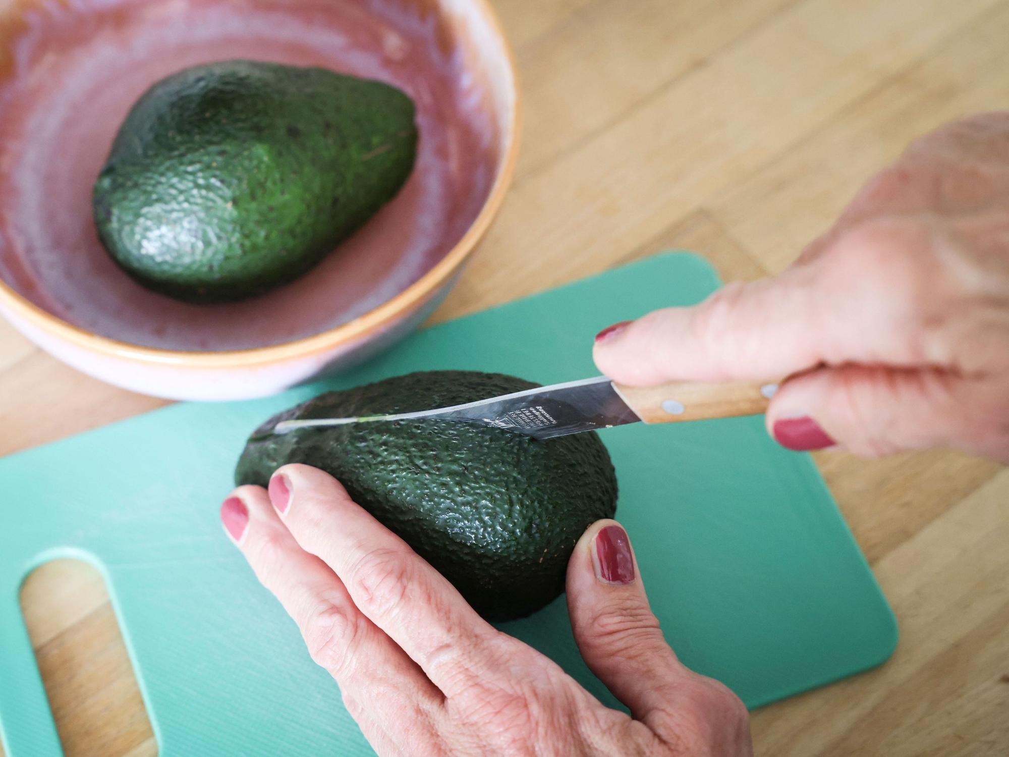 Eine Frau schneidet mit einem Messer eine Avocado auf. Die Zahlen zu Fällen von Schnittverletzungen beim Aufschneiden von Avocados sind gestiegen. (Symbolfoto)