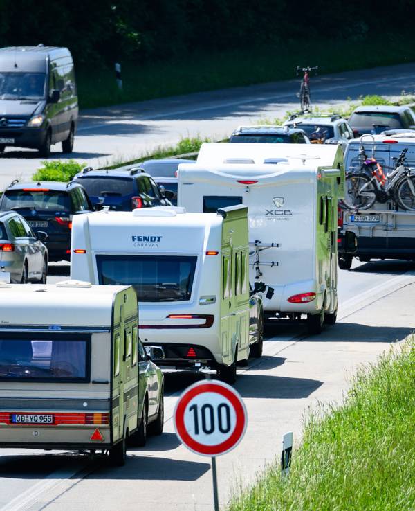 Zahlreiche Wohnmobile, Wohnwagen und Autos stehen im Autobahn-Stau.