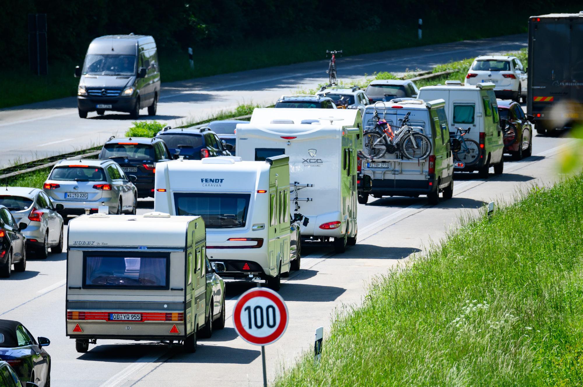 Zahlreiche Wohnmobile, Wohnwagen und Autos stehen im Autobahn-Stau.
