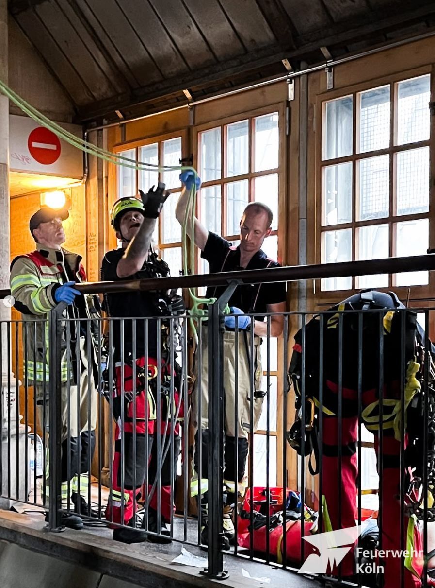 Einsatzkräfte von Feuerwehr und Höhenrettung bereiten ein Seil vor, das von der Decke hängt.