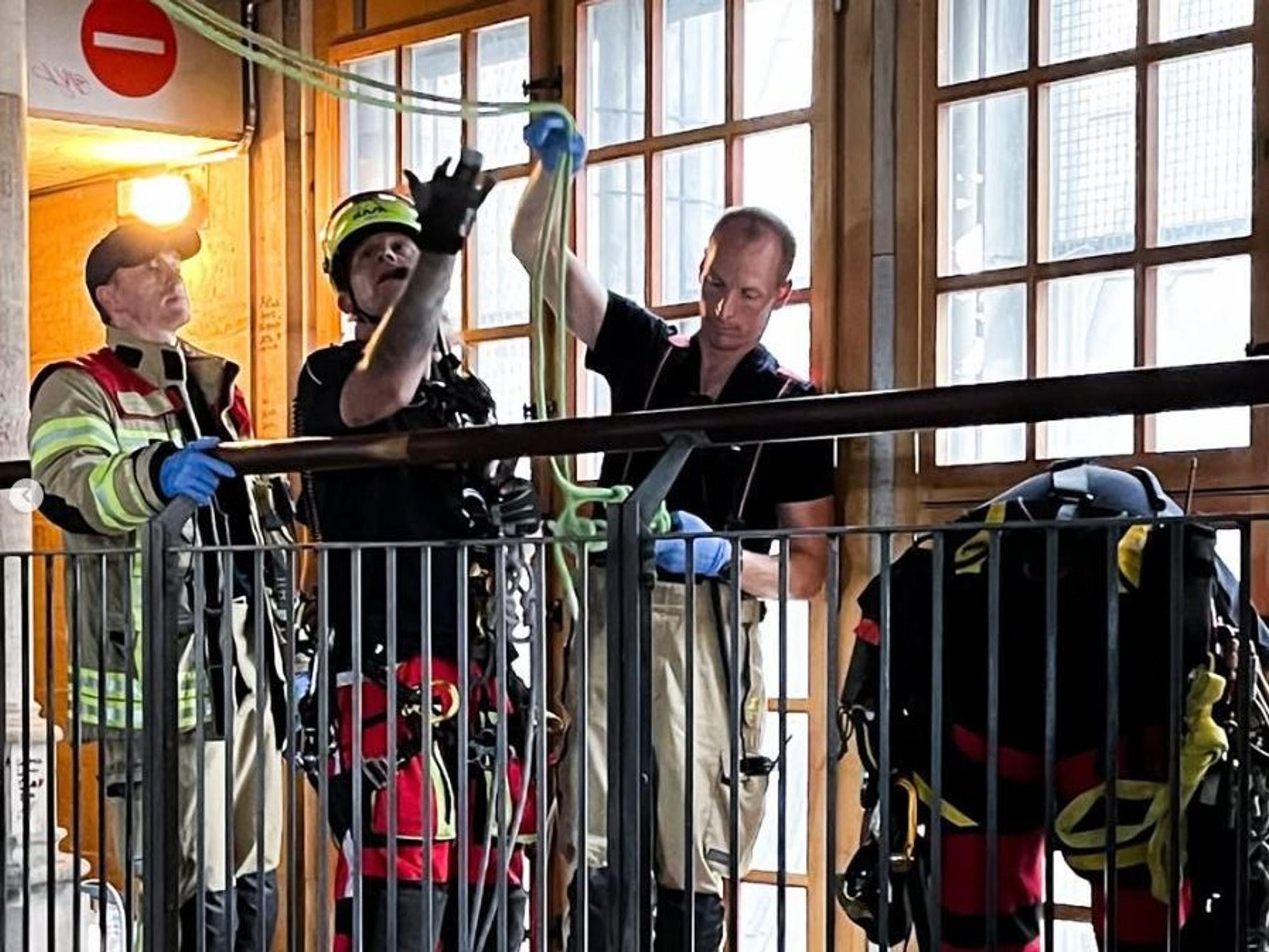 Einsatzkräfte von Feuerwehr und Höhenrettung bereiten ein Seil vor, das von der Decke hängt.