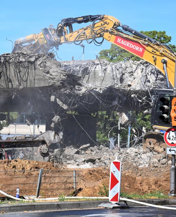 Ein Bagger reißt ein Stück einer Brücke ab.