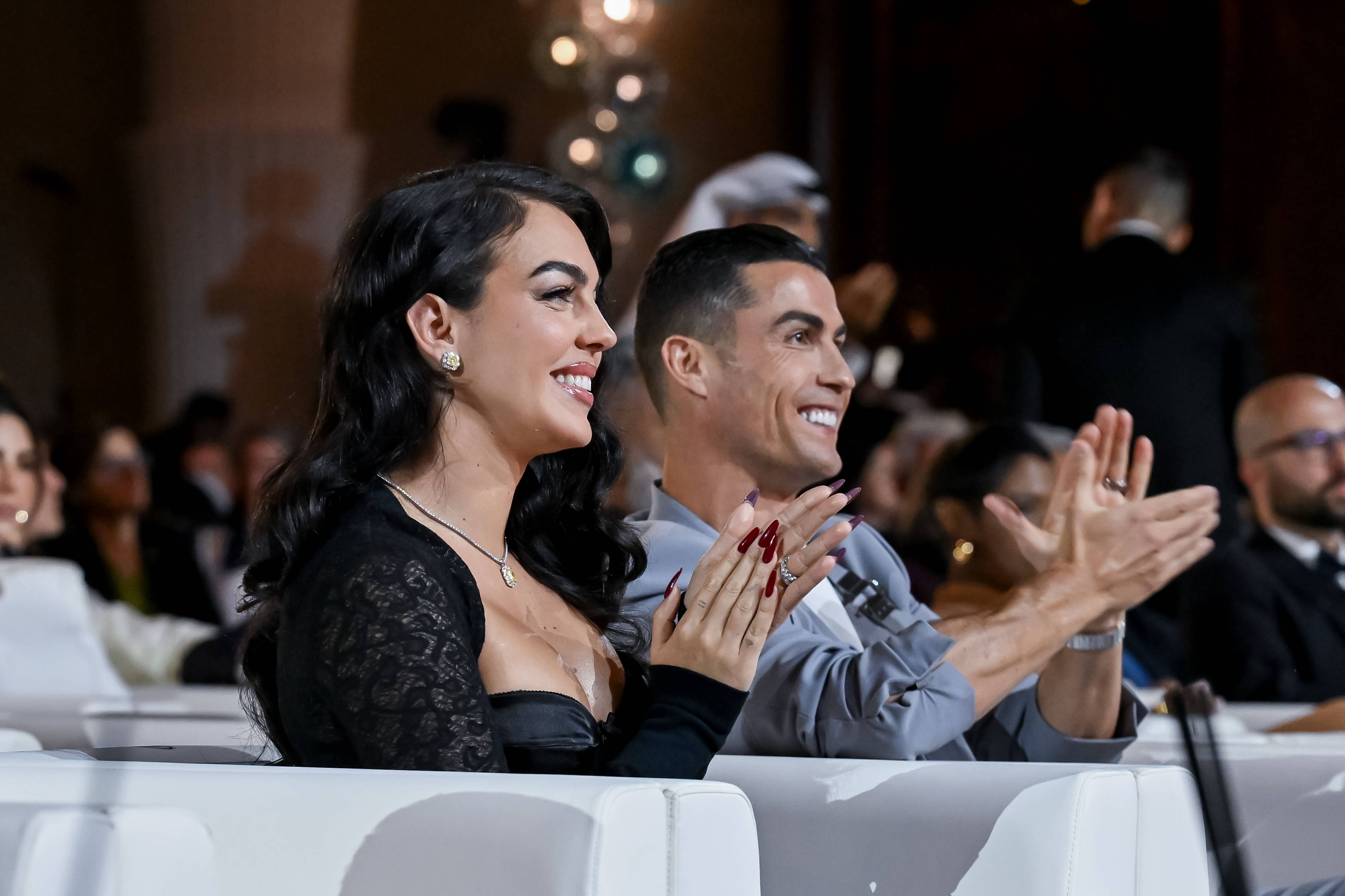 Georgina Rodríguez sitzt neben Cristiano Ronaldo und beide applaudieren.