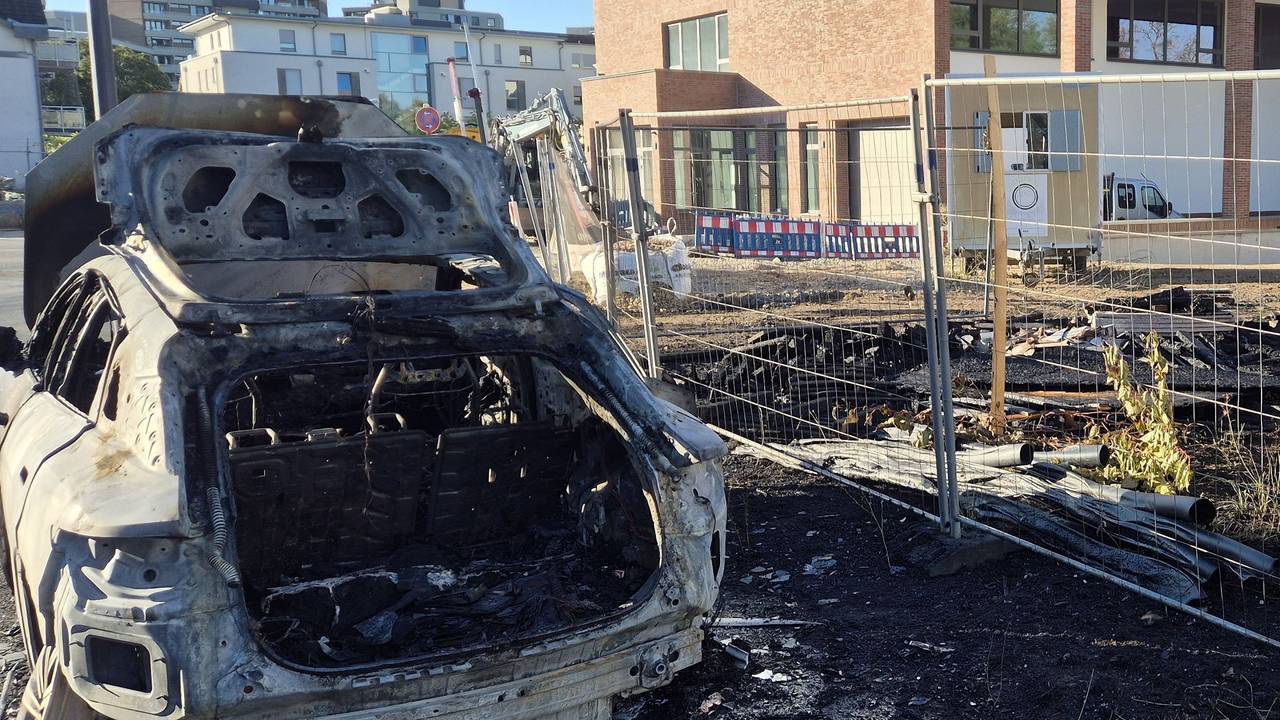 Ein ausgebranntes Fahrzeug steht an einer Baustelle.