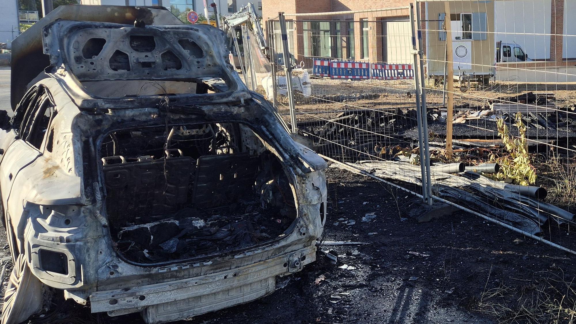 Ein ausgebranntes Fahrzeug steht an einer Baustelle.
