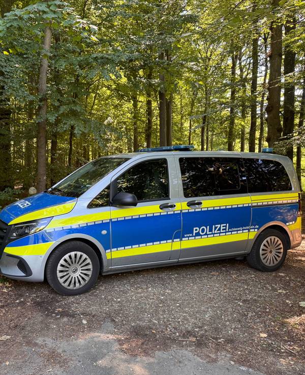 Ein Einsatzfahrzeug der Polizei steht vor einem Waldstück im Landkreis Schleswig-Flensburg. In der Nähe von Flensburg hat ein Jäger einen in Plastikfolie verpackten Torso eines Mannes gefunden. Die Polizei geht von einem Gewaltverbrechen aus und sucht nach weiteren Spuren.