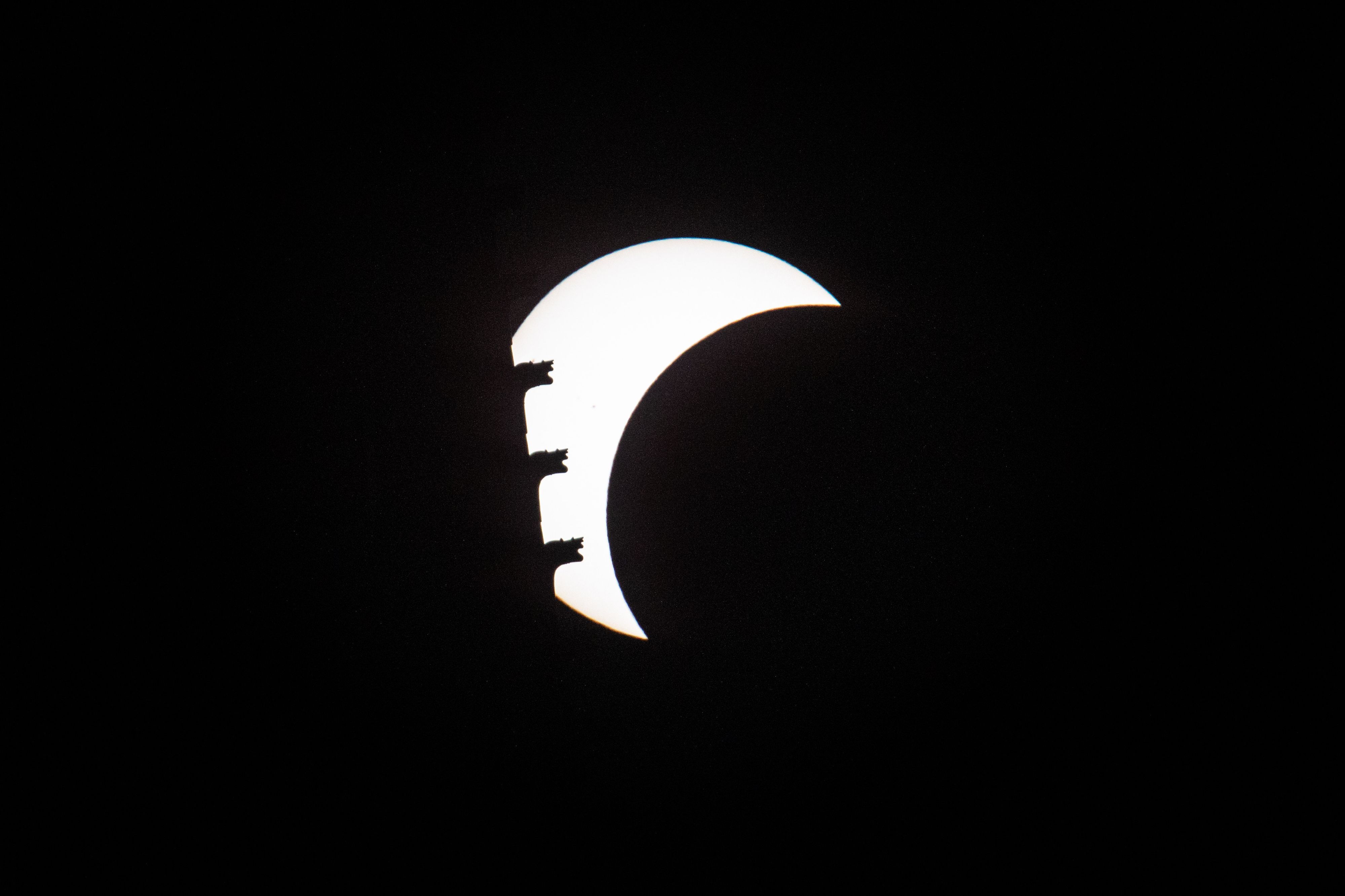 Die Sonne zeigt sich bei einer partiellen Sonnenfinsternis teilweise vom Mond bedeckt. Teile des Kölner Dom verdecken die verbleibende Sichel.
