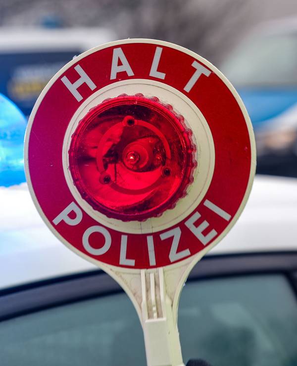 Ein Polizist hält eine Polizeikelle für eine Kontrolle. (Symbolfoto)