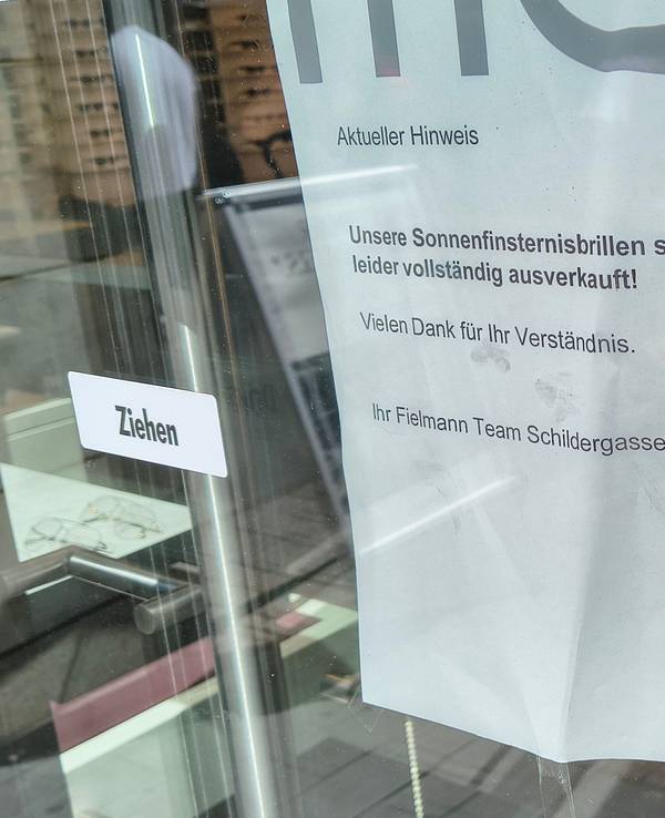 An der Tür eines Optikergeschäfts in der Kölner Innenstadt steht ein Schild mit der Aufschrift „Unsere Sonnenfinsternisbrillen sind leider vollständig ausverkauft!“.