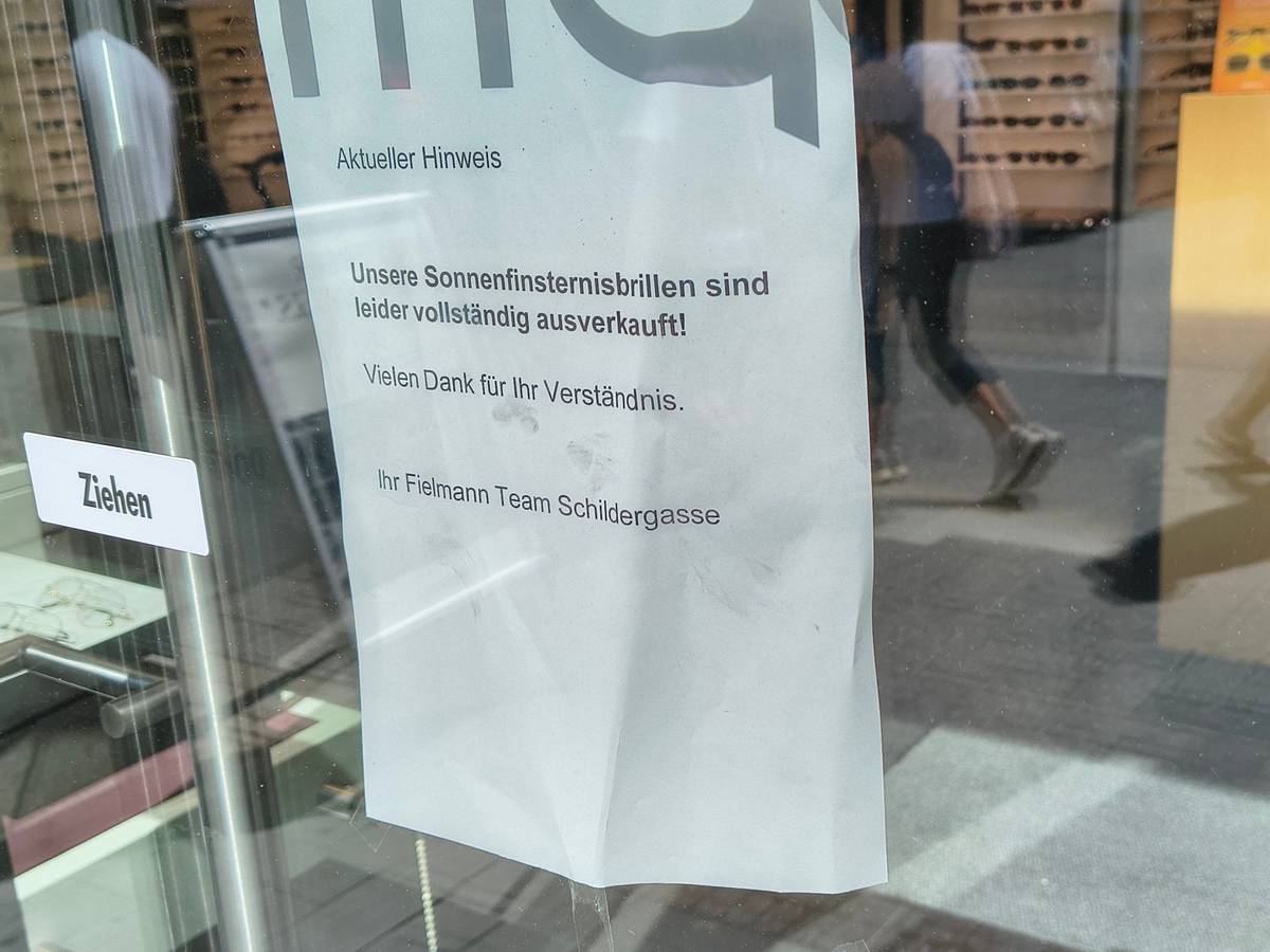 An der Tür eines Optikergeschäfts in der Kölner Innenstadt steht ein Schild mit der Aufschrift „Unsere Sonnenfinsternisbrillen sind leider vollständig ausverkauft!“.