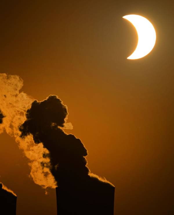 Die partielle Sonnenfinsternis ist am Himmel über dem Braunkohlekraftwerk Neurath in Pulheim bei Köln zu sehen.
