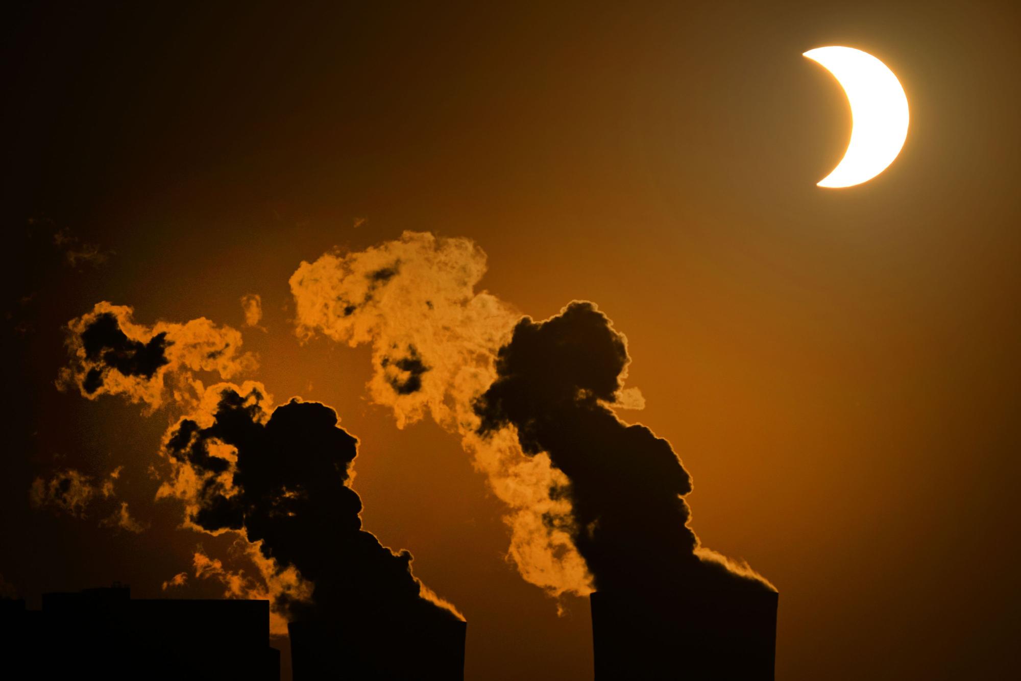 Die partielle Sonnenfinsternis ist am Himmel über dem Braunkohlekraftwerk Neurath in Pulheim bei Köln zu sehen.