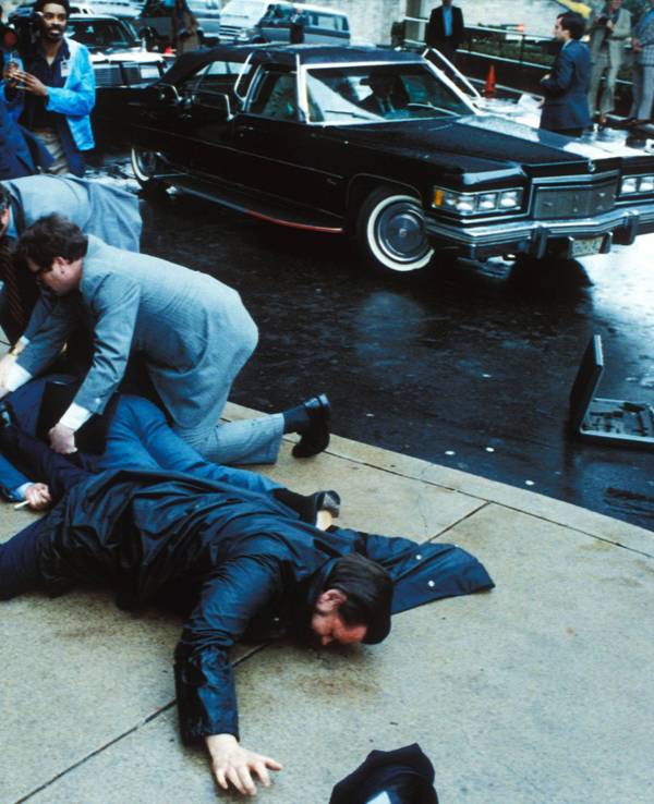 Unmittelbar nach den Schüssen auf US-Präsident Ronald Reagan überwältigen Sicherheitskräfte den Attentäter John Hinckley Jr. vor dem Washington Hilton Hotel, während der schwer verletzte Regierungssprecher James Brady und ein Polizist am Boden liegen.
