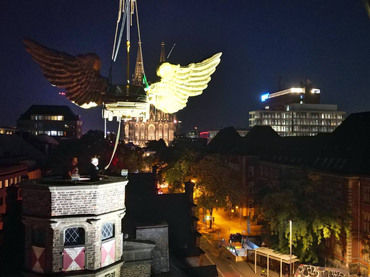 Das goldene Flügelauto des Kölner Künstlers HA Schult wird von einem Kran vom Turm des historischen Zeughauses gehoben.