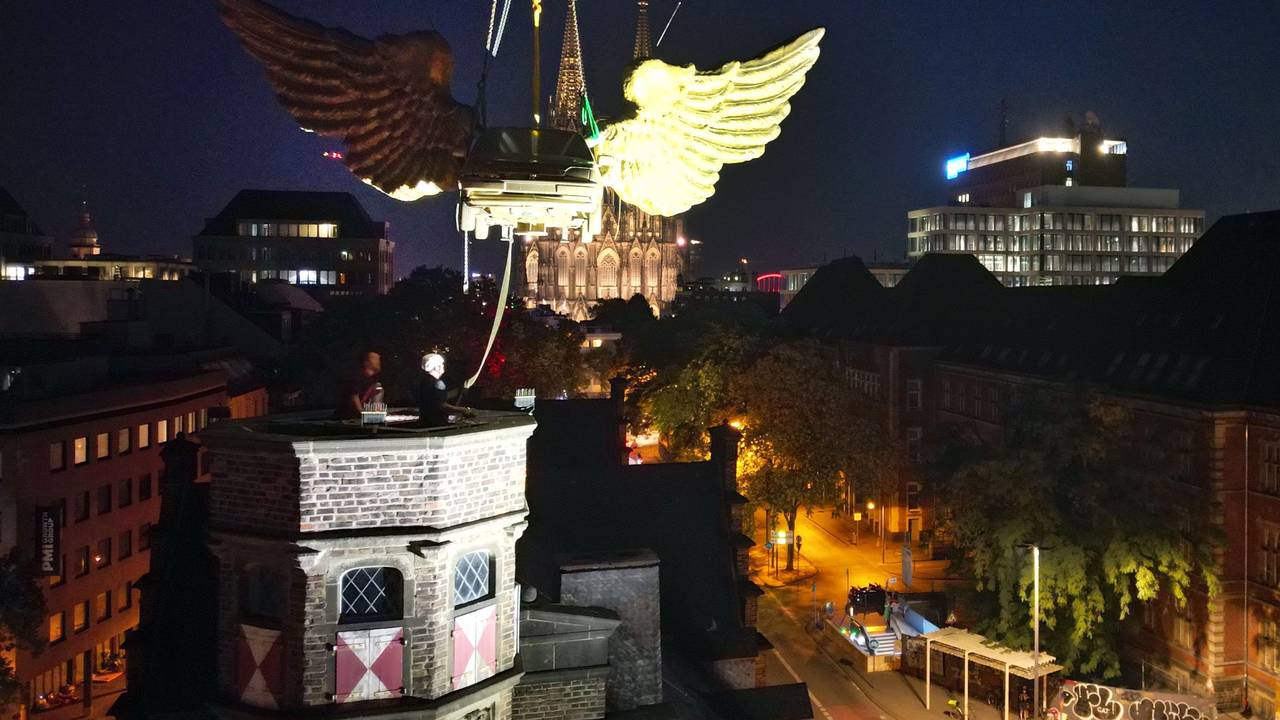 Das goldene Flügelauto des Kölner Künstlers HA Schult wird von einem Kran vom Turm des historischen Zeughauses gehoben.