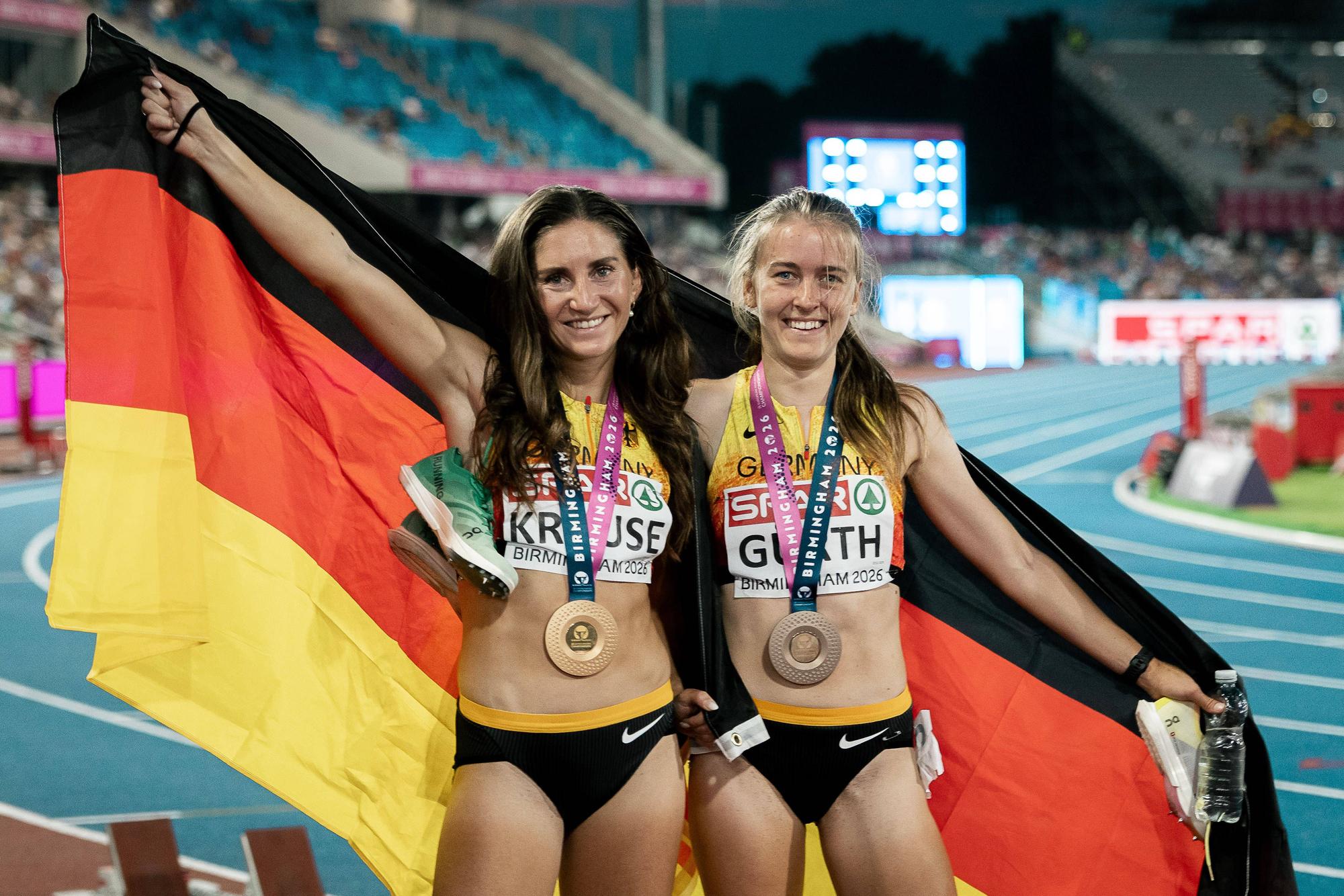 Gesa Krause und Olivia Gürth posieren mit Medaillen und Flagge.