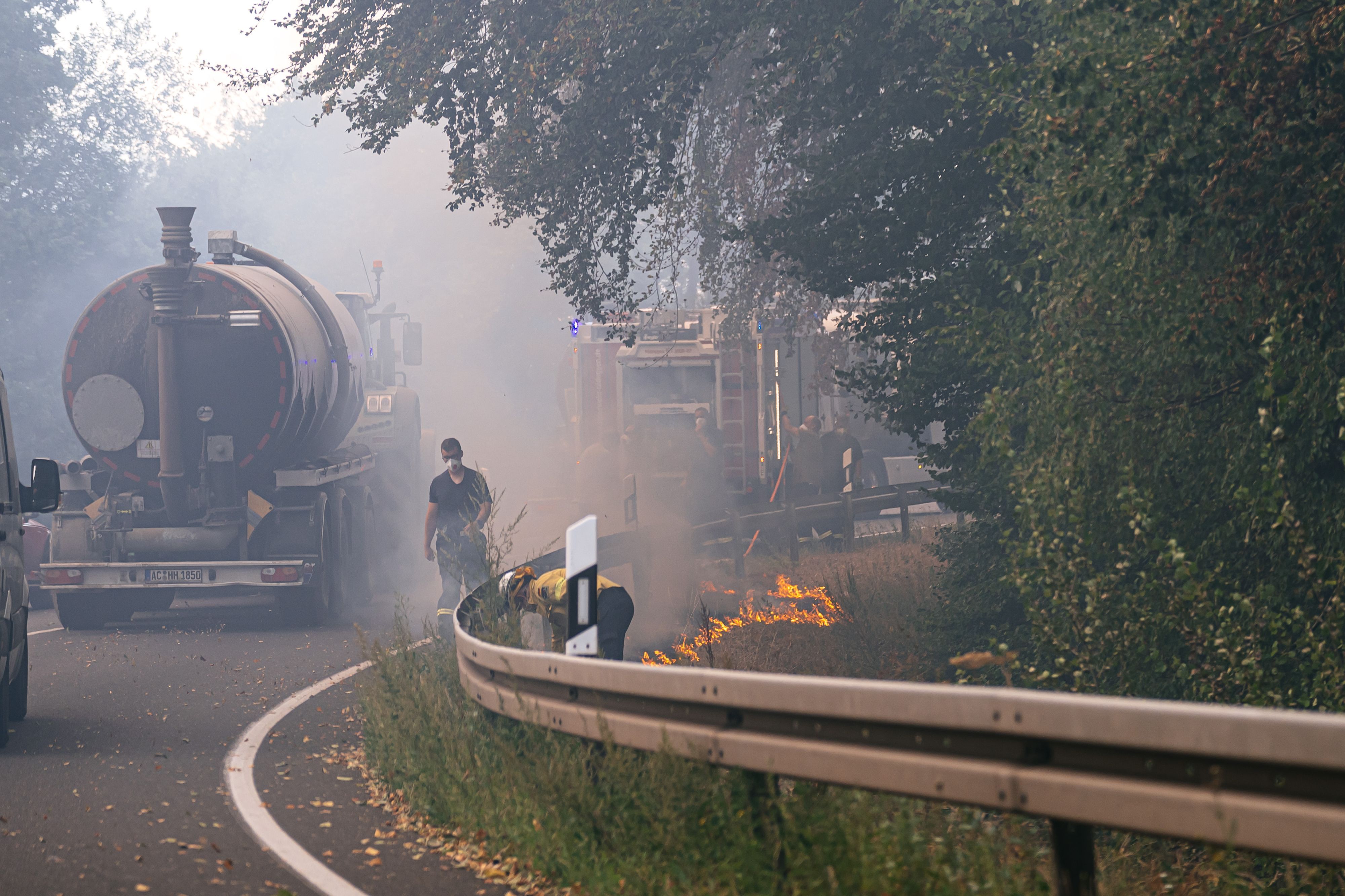Am Straßenrand legen Einsatzkräfte ein sogenanntes Gegenfeuer und setzen Vegetation kontrolliert in Brand. So soll dem eigentlichen Feuer die Nahrung entzogen werden, wenn es die Stelle erreicht.