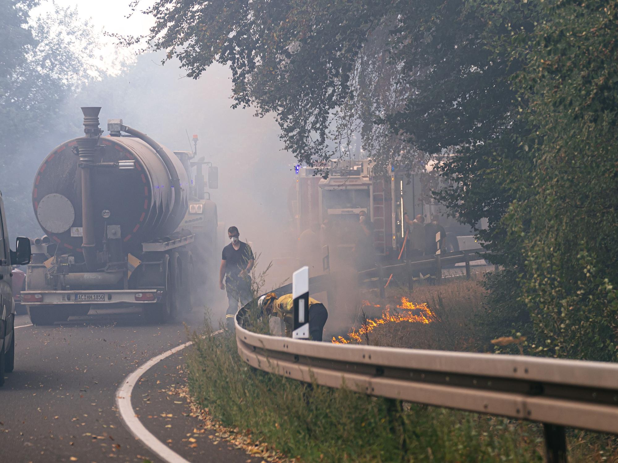 Am Straßenrand legen Einsatzkräfte ein sogenanntes Gegenfeuer und setzen Vegetation kontrolliert in Brand. So soll dem eigentlichen Feuer die Nahrung entzogen werden, wenn es die Stelle erreicht.