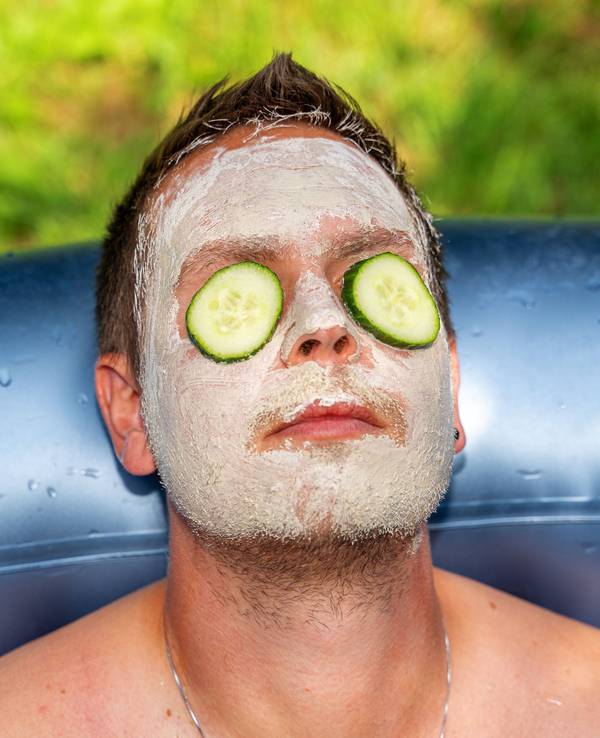 Mann mit Gurken und Gesichtsmaske aus Schlamm im Gesicht