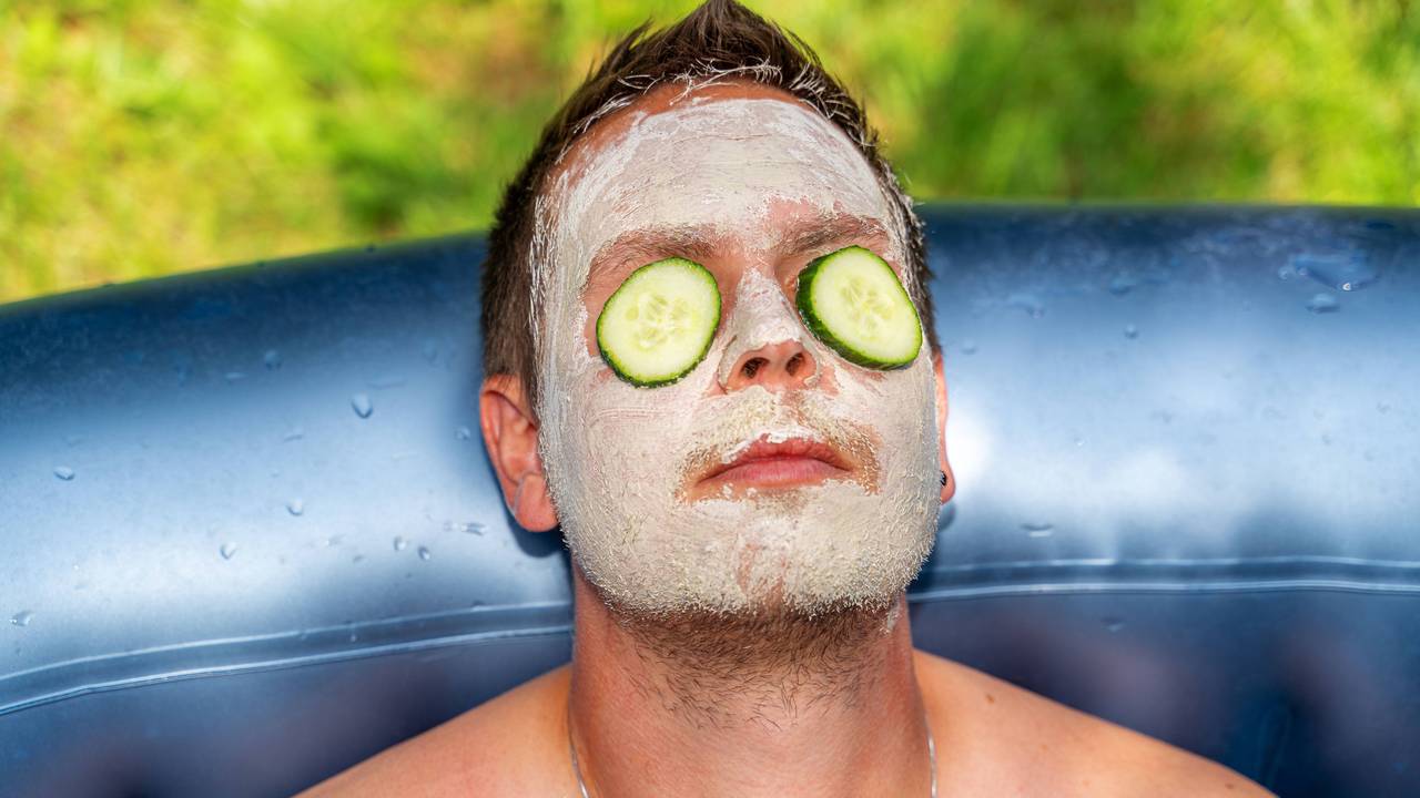 Mann mit Gurken und Gesichtsmaske aus Schlamm im Gesicht
