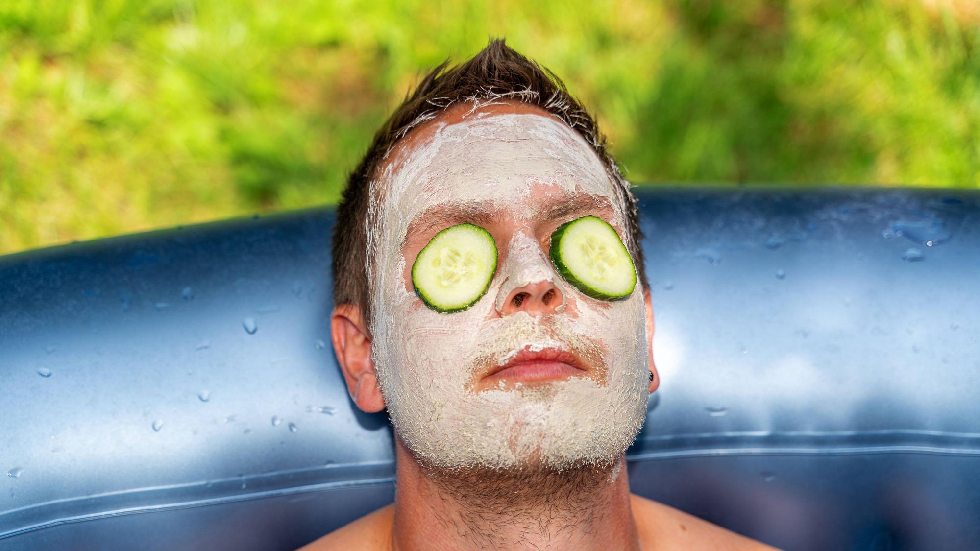 Mann mit Gurken und Gesichtsmaske aus Schlamm im Gesicht