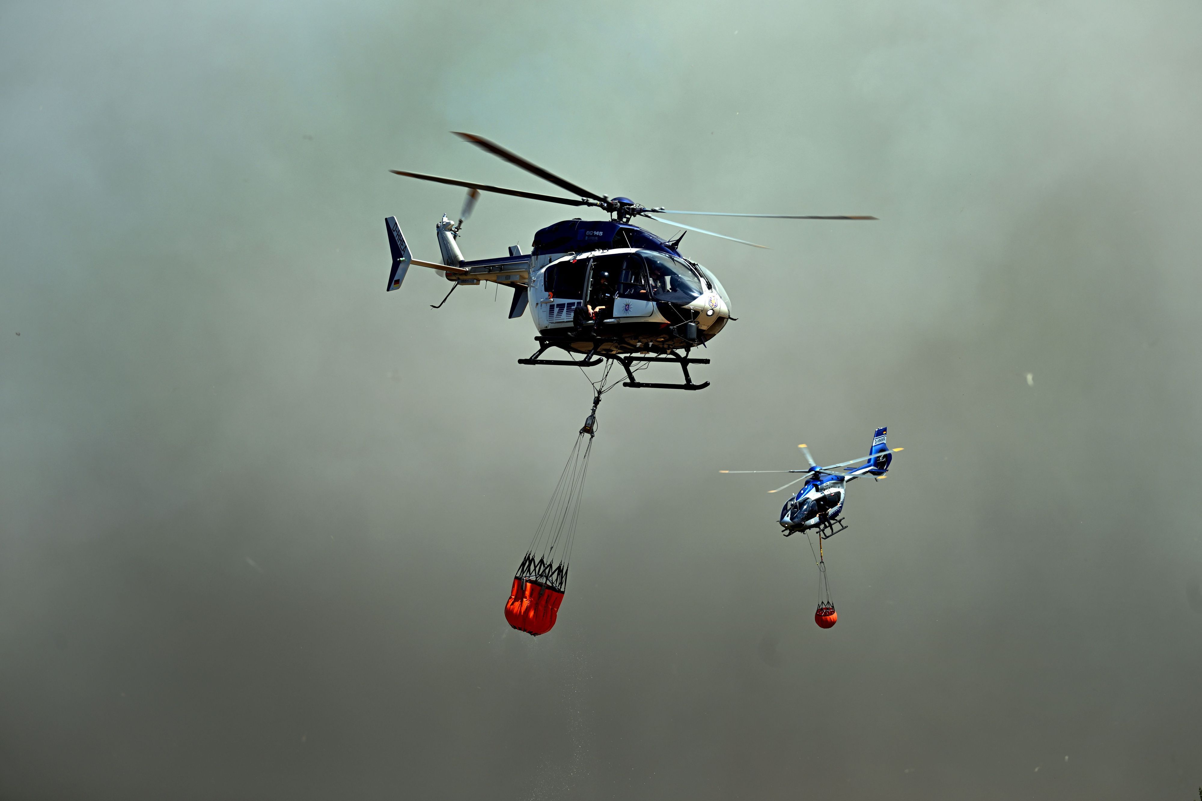 Helikopter fliegen an, um Wasser in Löschwasser-Außenlastbehältern zum Einsatz beim Waldbrand im Hürtgenwald aufzunehmen.