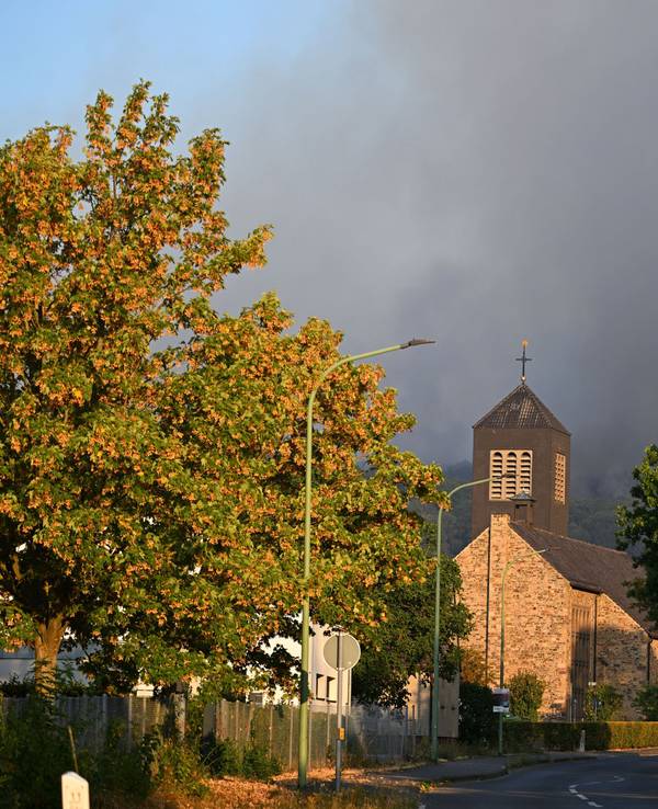 Dichter Rauch eines Waldbrands im Hürtgenwald steigt hinter der Kirche des Ortsteils Gey auf.