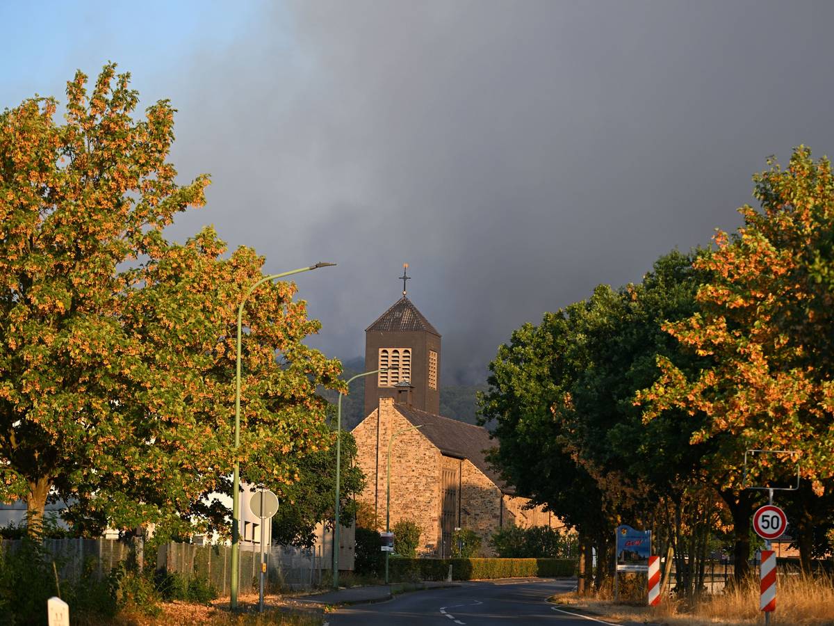 Dichter Rauch eines Waldbrands im Hürtgenwald steigt hinter der Kirche des Ortsteils Gey auf.