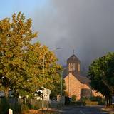 Dichter Rauch eines Waldbrands im Hürtgenwald steigt hinter der Kirche des Ortsteils Gey auf.