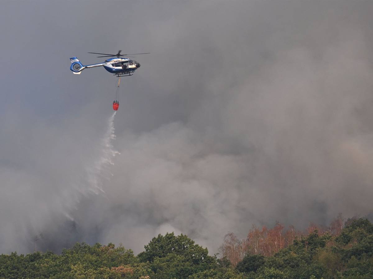 Ein Polizeihubschrauber mit Löschwasser-Außenlastbehälter unterstützt die Löscharbeiten beim Waldbrand im Hürtgenwald.