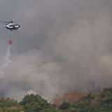 Ein Polizeihubschrauber mit Löschwasser-Außenlastbehälter unterstützt die Löscharbeiten beim Waldbrand im Hürtgenwald.