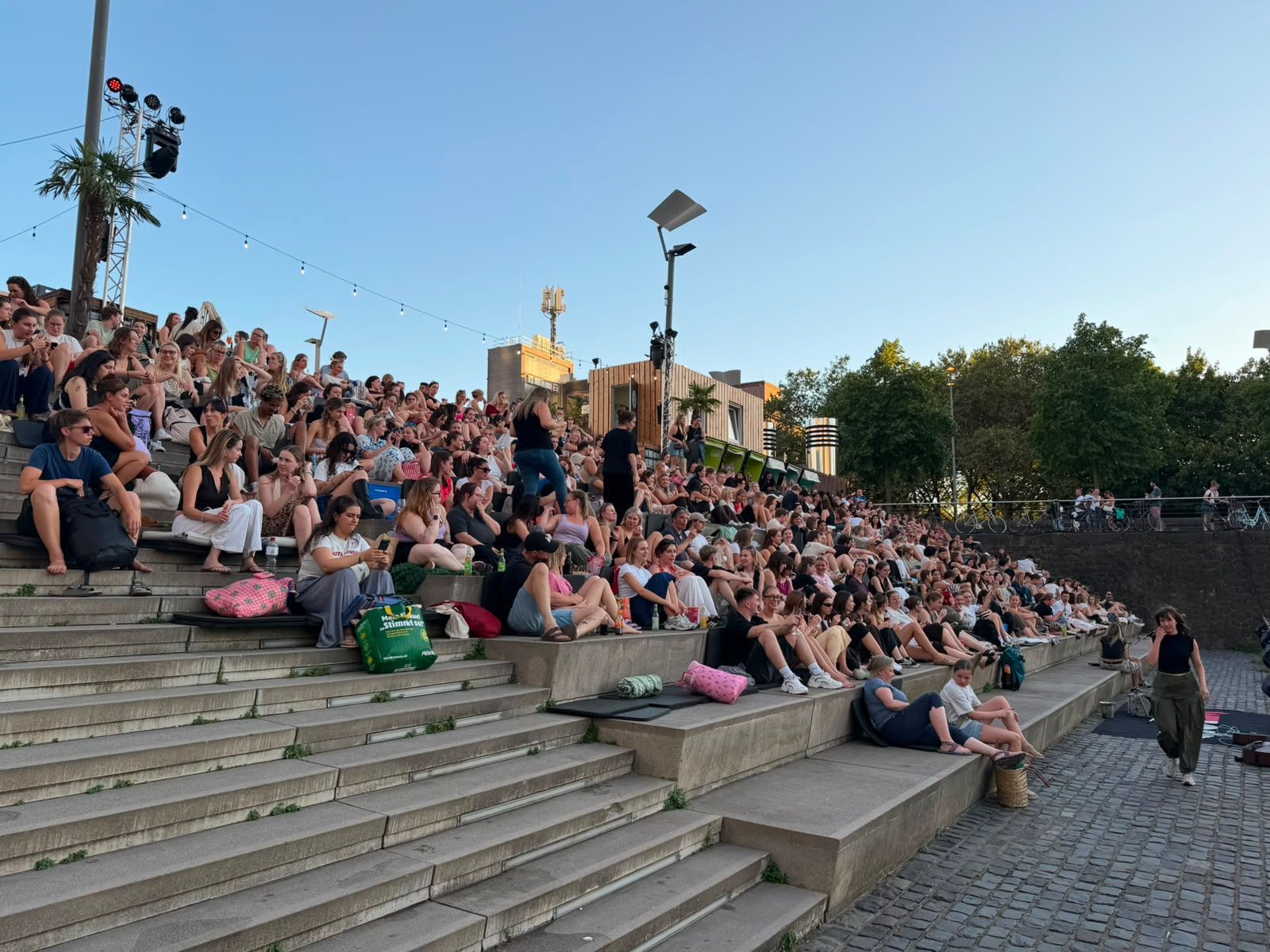 Menschen sitzen auf den Treppen im Kölner Rheinauhafen.