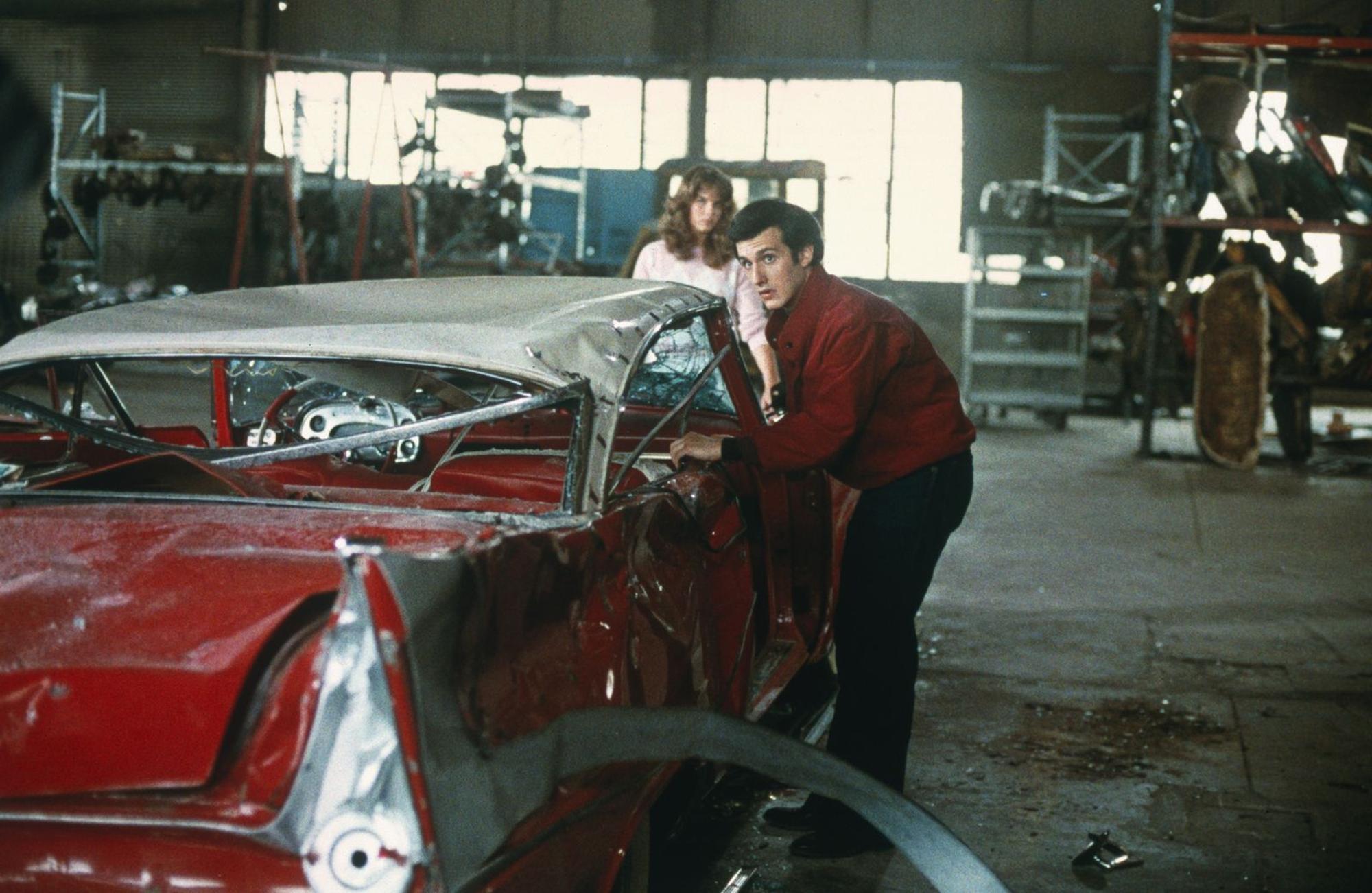 Arnie (Keith Gordon) und Leigh (Alexandra Paul) entdecken die völlig demolierte Christine in einer Werkstadt. (Bild: ZDF/© 1983 Columbia Pictures Industries, Inc. All Rights Reserved)