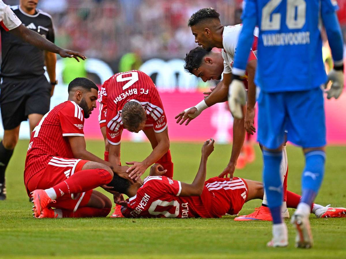 Jamal Musiala liegt auf dem Rasen, Ismael Saibari und Joshua Kimmich kümmern sich um ihn.
