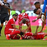 Jamal Musiala liegt auf dem Rasen, Ismael Saibari und Joshua Kimmich kümmern sich um ihn.