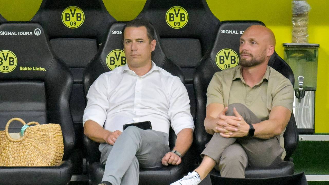 Lars Ricken und Ole Book sitzen auf der BVB-Ersatzbank.