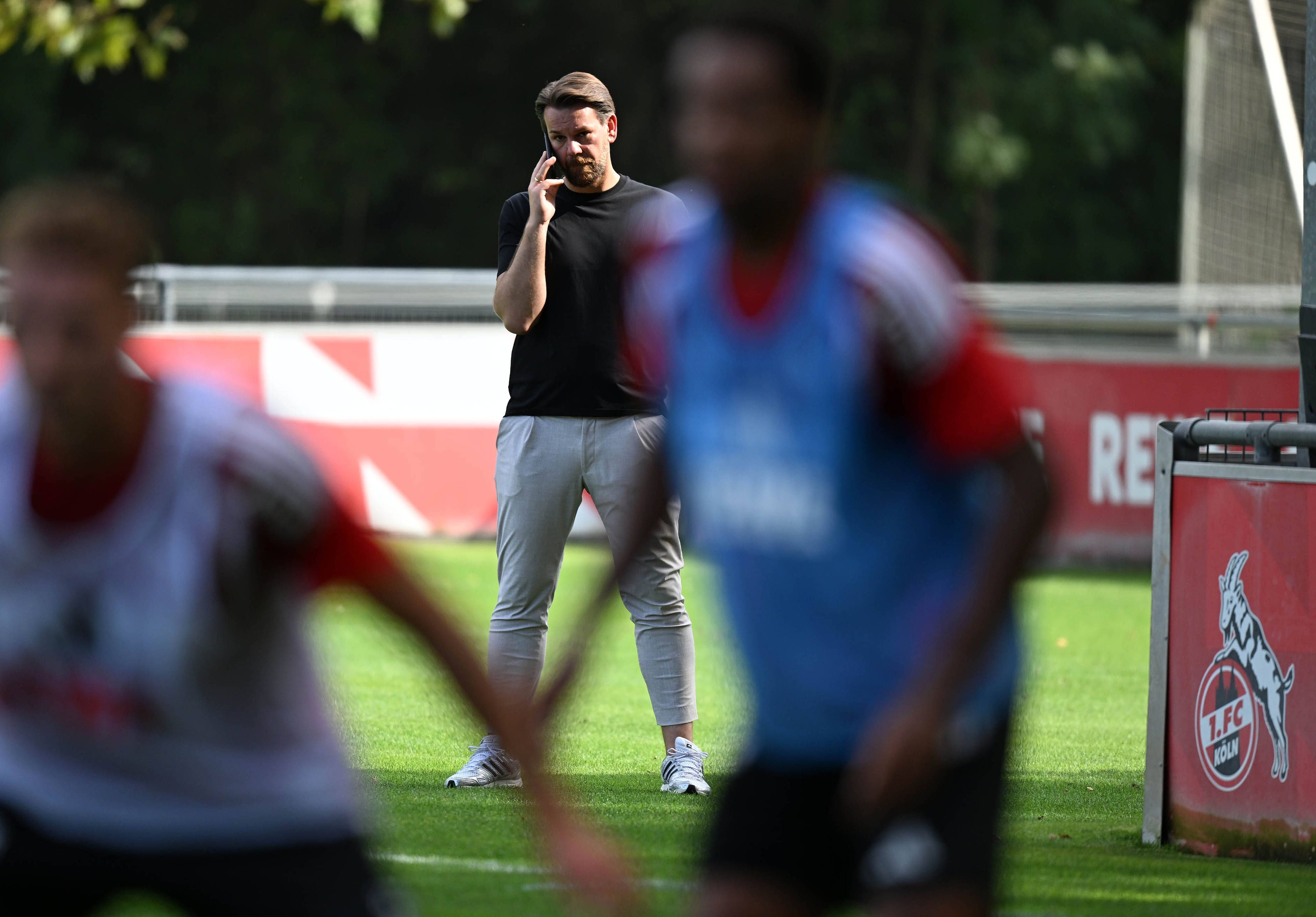 Thomas Kessler telefoniert, während er das FC-Training beobachtet.