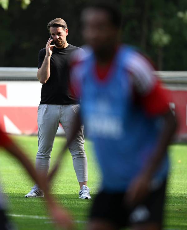 Thomas Kessler telefoniert, während er das FC-Training beobachtet.