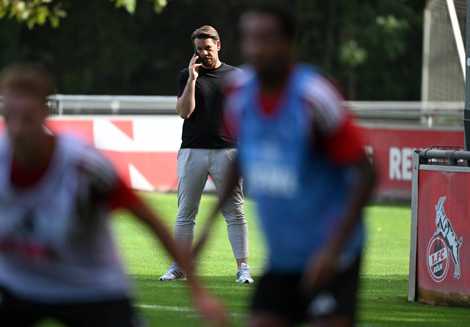 Thomas Kessler telefoniert, während er das FC-Training beobachtet.
