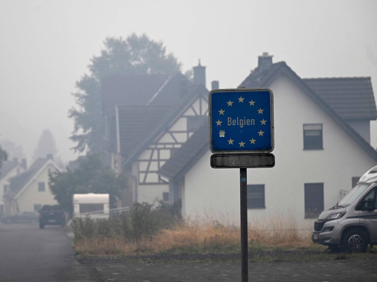 Auf dem Foto ist ein Wegweiser zur belgischen Grenze zu sehen, während am 17. August 2026 Rauch über den Häusern in Kalterherberg bei Monschau in Westdeutschland hängt.