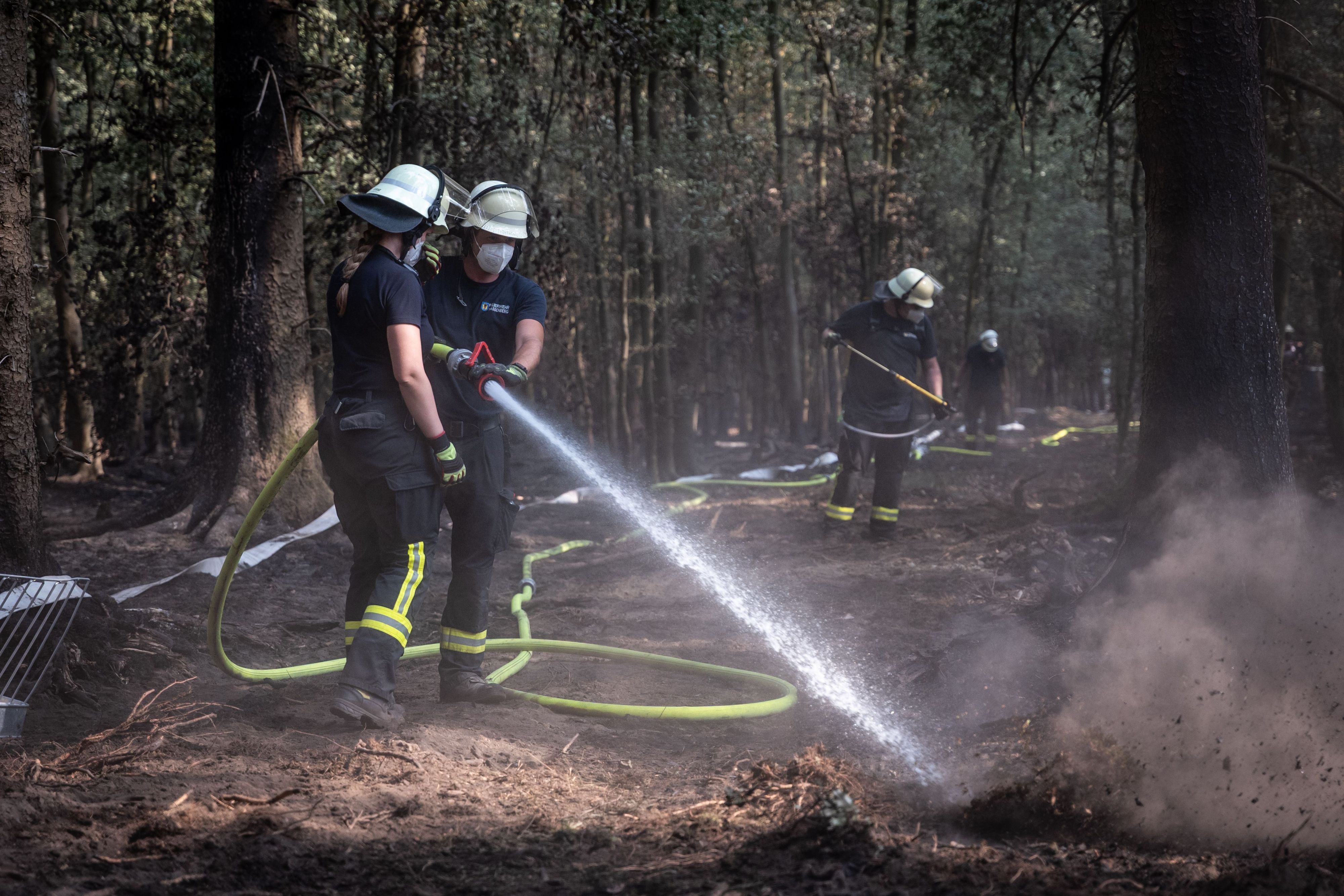 Feuerwehrmänner sind bei Nachlöscharbeiten in einem Waldstück im Hürtgenwald im Einsatz.
