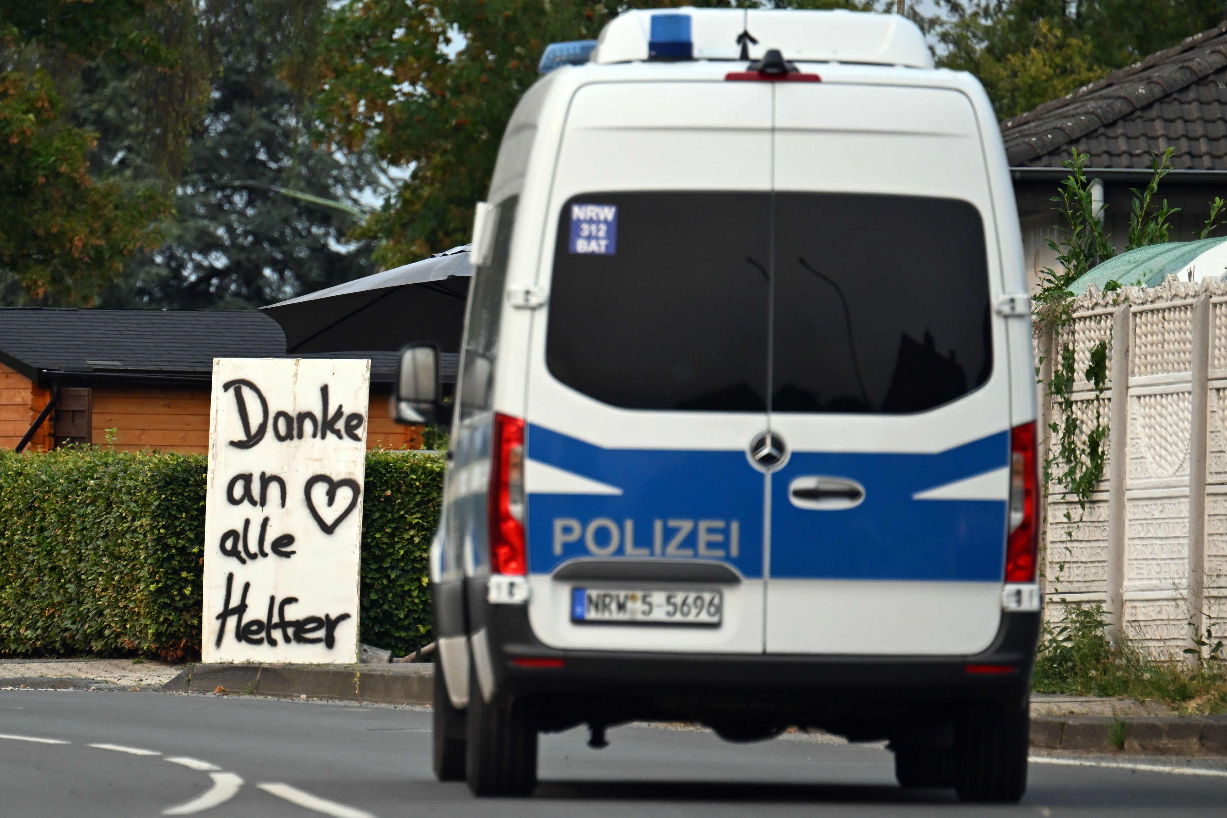 Ein Polizeifahrzeug fährt an einem Schild mit der Aufschrift „Danke an alle Helfer“ vorbei.  unter Kontrolle gebracht.