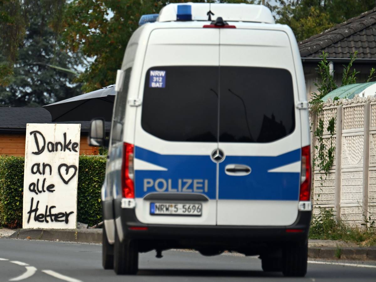 Ein Polizeifahrzeug fährt an einem Schild mit der Aufschrift „Danke an alle Helfer“ vorbei. unter Kontrolle gebracht.