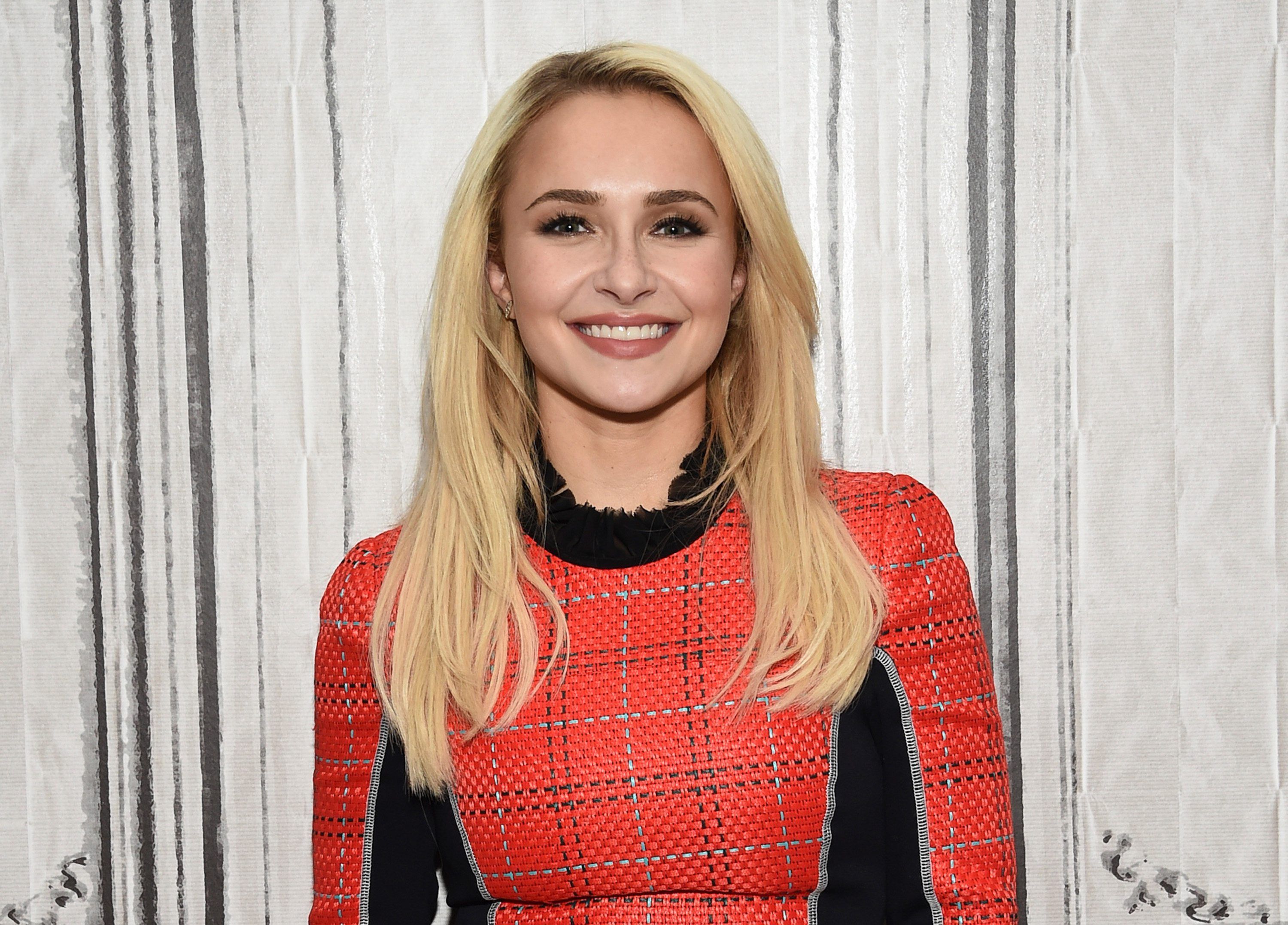 Hayden Panettiere mit blonden Haaren und rotem Oberteil lächelt.