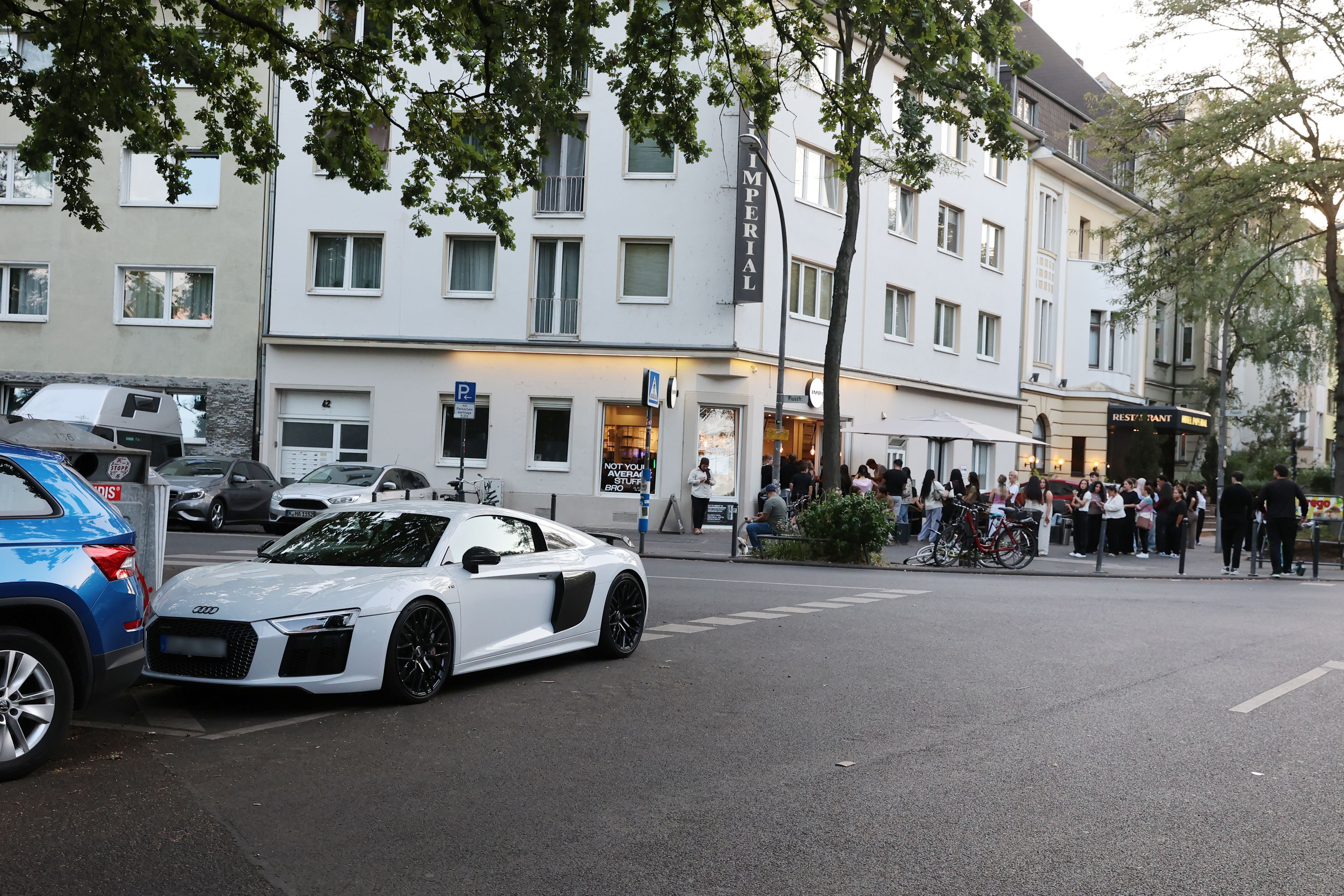 Seit Monaten schwelt ein Nachbarschaftstreit in Ehrenfeld rund um das Hype-Cafe Impi. Dort stömen Influencer, junge Menschen und Autoposer hin. Nachbarn beschweren sich über Lärm, Müll und Respektlosigkeiten