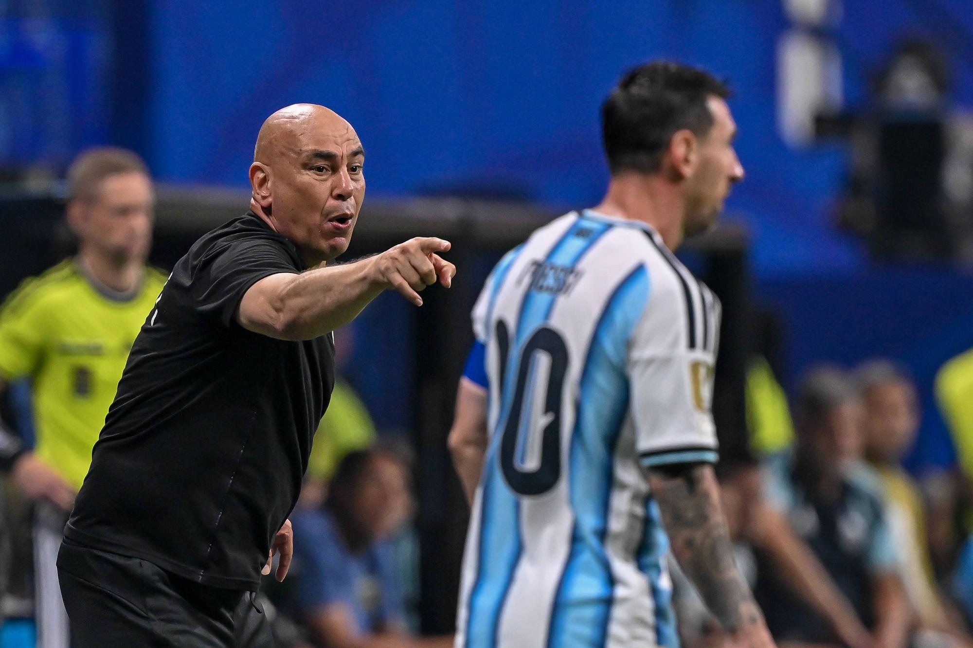 Hossam Hassan gestikuliert an der Seitenlinie. Im Vordergrund ist Lionel Messi unscharf zu sehen.