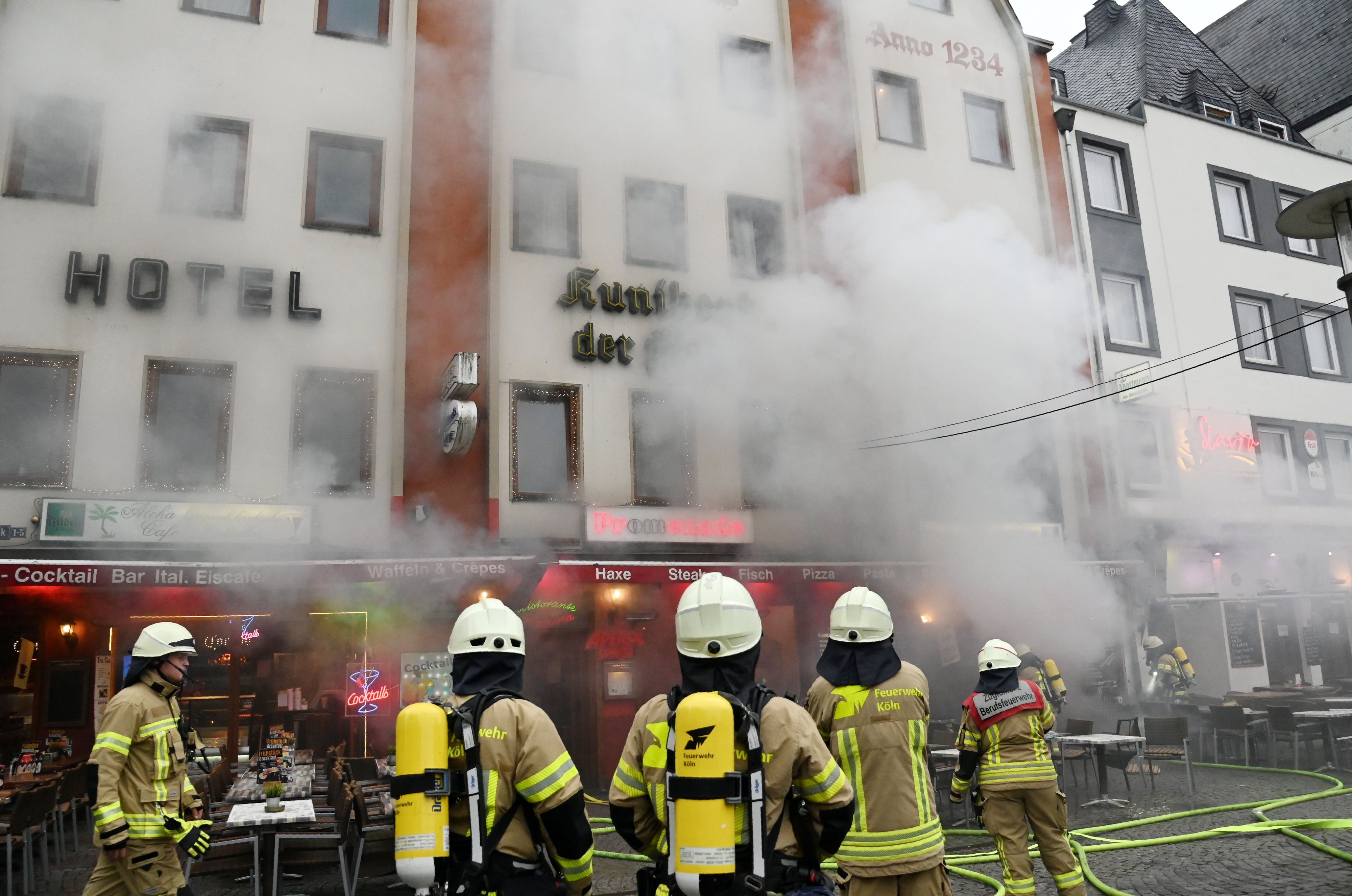 Feuerwehrleute stehen vor einem Gebäude, aus dem dichter Qualm dringt.